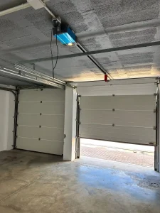 Garaje interior amplio con dos puertas automáticas, suelo de hormigón y salida al exterior.